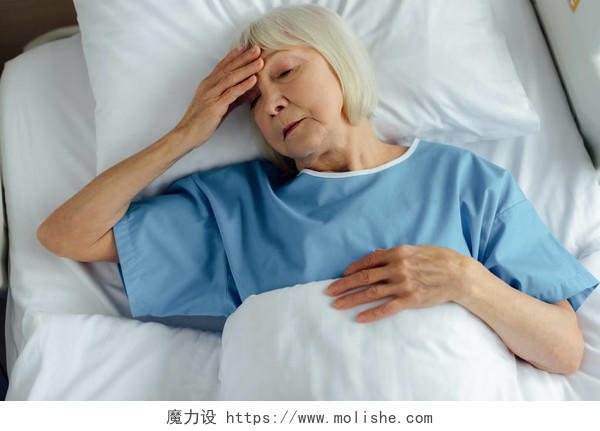 心烦意乱的老年妇女躺在病床上触摸额头和头痛头晕